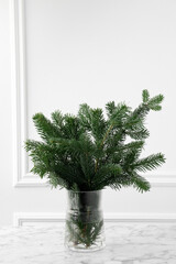 Fototapeta premium Beautiful fir tree branches on table near white wall. Christmas decor