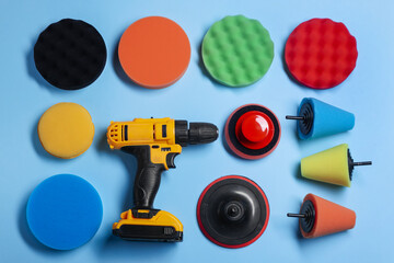 Electric screwdriver with different polish pads on light blue background, flat lay