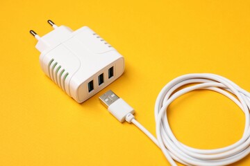 USB power adapter and charge cable on orange background, closeup