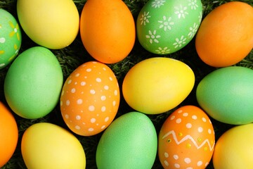 Beautiful decorated Easter eggs on green grass, flat lay