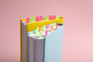 Books with colorful tabs on pink background, closeup