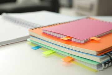 Notebooks with colorful tabs on light table, closeup