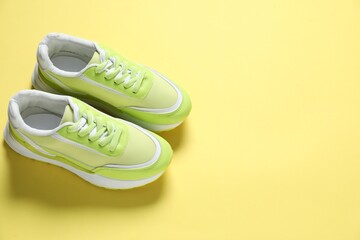 Sportive shoes. Green sneakers on yellow background, above view. Space for text