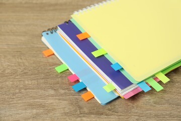Notebooks with colorful tabs on wooden table, closeup