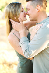 Fototapeta premium Smiling young man hugging and almost kissing woman in garden