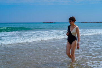 adult woman strolling along the beach enjoying the sea waves