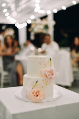 Wedding cake decorated with flowers stands on a tray on the table