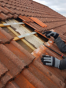 man replaces broken roof shingles on the rooftop with new ones. closeup shot