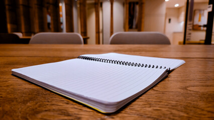 Open lined notebook and ballpoint pen on wooden table for study concept
