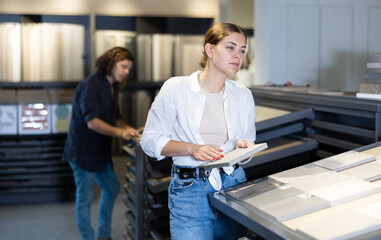 Confident woman looking to buy bathroom wall tiles in materials section of hardware store