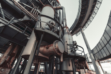 Industrial metal structure with large cylindrical tanks, pipes, valves, and railings. Rusted...