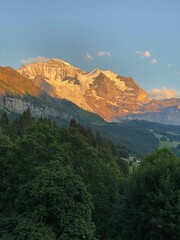 The orange color of a sunset reflecting on a mountain of the swiss alps