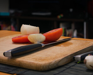 Tomatoes, peppers and onions on a cutting board on a dark background, Preparation of a vegetable salad with fresh tomatoes, pepper, garlic and onions. Chopped garlic on a wooden cutting board and fres