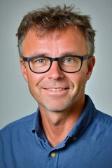 Obraz premium Smiling caucasian mature male with glasses in blue shirt portrait