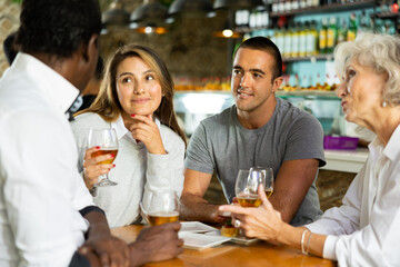 Happy diverse group having a conversation at a bar with beer