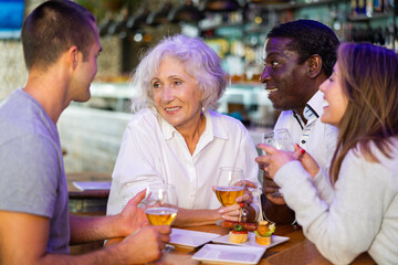Happy diverse group having a conversation at a bar with beer