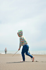 Happy child walking with stick and sand on sea beach in the sun