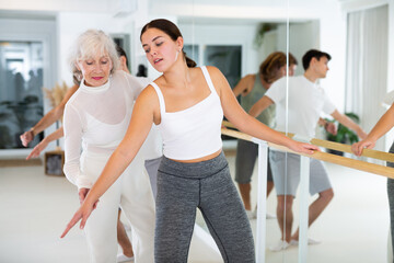 Fototapeta premium Female ballet teacher showing moves in front of a group of different aged dancers in dancing studio