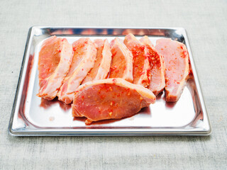 Juicy pork chops on a metal tray. Meat in red spicy sauce. Food preparation and enchanting taste. Popular product.