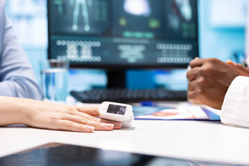 Physician using an oximeter on patient to measure oxygen levels and saturation, checking vital signs during a medical examination at facility. Medic consulting a woman on health insurance. Close up.