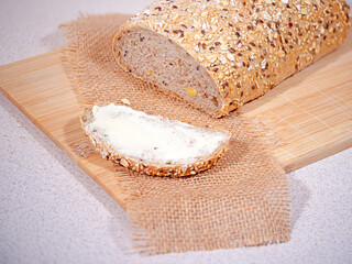 A slice of buttered white bread on a wooden kitchen chopping board.