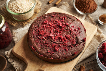 Round gluten-free brownie cake made of red kidney beans, oat flakes, chocolate and freeze-dried raspberries