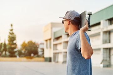 Skater holding skateboard looking away in urban environment