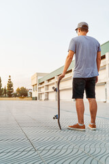 Young skater holding his skateboard is looking at the skatepark