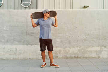 Skater holding skateboard behind neck in urban setting