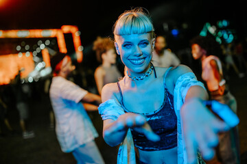 Fototapeta premium Young woman dancing and reaching out at a music festival