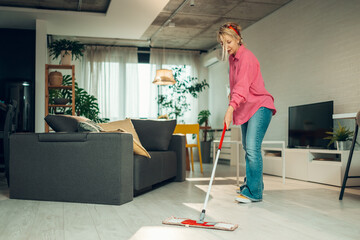 Woman cleaning modern living room with mop
