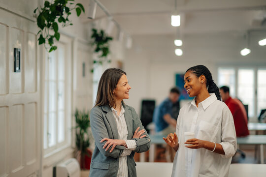 Two businesswomen talking during coffee break in modern office