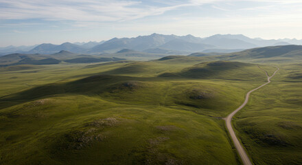 Naklejka premium Scenic Rural Landscape with Green Hills and Mountains Under Expansive Sky