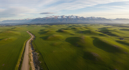 Drone View of Scenic Road Through Green Hills and Mountains under Cloudy Sky