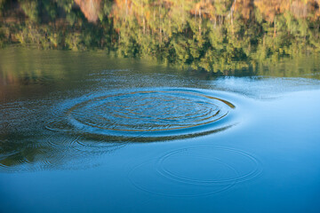 Circular water ripples and bubbles effect. Water ripples and round droplets on blue sea texture pattern background. Liquid motion on calm lake surface. Ring affect, circles