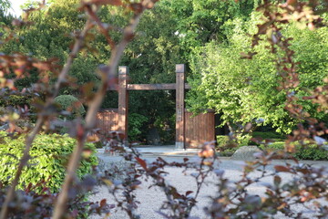 Asian-style wooden gate which overlooks thickets of trees and Bushes (white red garden)
