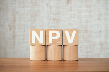 There is wood cube with the word NPV. It is an abbreviation for Net Present Value as eye-catching...