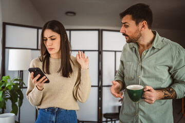 Jealous man spying his wife mobile phone while she is reading message