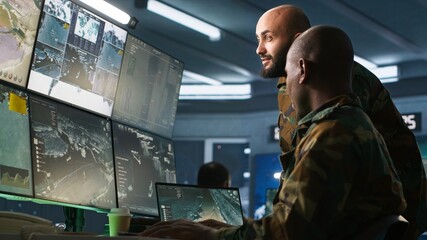 Army colleagues looking at screens in command center housing operational missile defense system designed to intercept ballistic rockets. Experts using tracking gear and radar systems, camera A