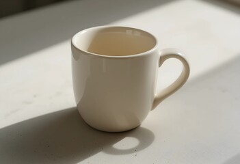 A ceramic mug with a smooth handle on a neutral surface. Soft lighting highlights its clean design and subtle texture. A simple, minimalist composition emphasizing warmth and everyday use.