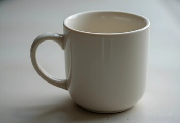 Fototapeta premium A ceramic mug with a smooth handle on a neutral surface. Soft lighting highlights its clean design and subtle texture. A simple, minimalist composition emphasizing warmth and everyday use.
