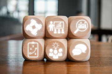 Wooden blocks with business icons symbolizing strategy, teamwork, and communication on a wooden...