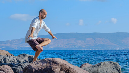 A middle-aged charismatic man, wearing a white shirt, is relaxing and enjoying the sun by doing...