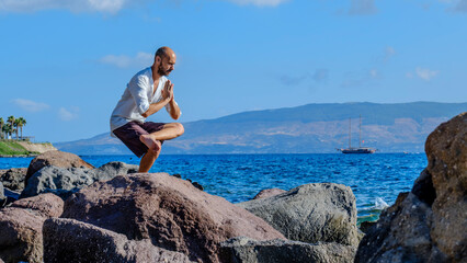 A middle-aged charismatic man, wearing a white shirt, is relaxing and enjoying the sun by doing...