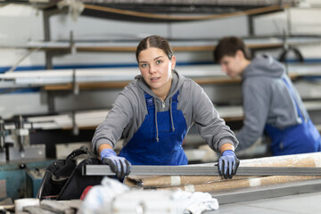 During work process, girl employee produces blanks for repairs and interior decoration. She carries...