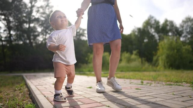 Mom and baby in hands and steps into the bathroom. Child mother family happy concept. Mom and baby walking in the park. Mom and baby walking in lifestyle park with. hands. family motherhood concept.