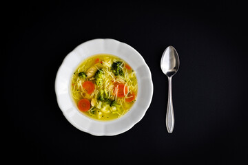 Warm vegetable soup served in a white bowl with spoon