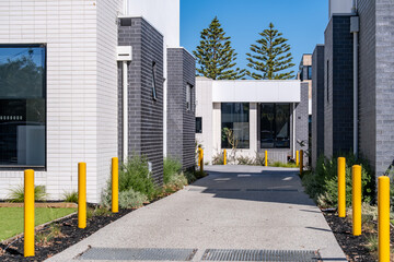 A modern residential or commercial complex entrance featuring contemporary-style townhouses. Safety...