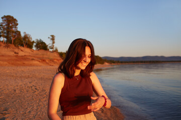 Portrait of a laughing girl. A happy girl walks on a sandy beach at sunset. Summer travel, vacations at sea.