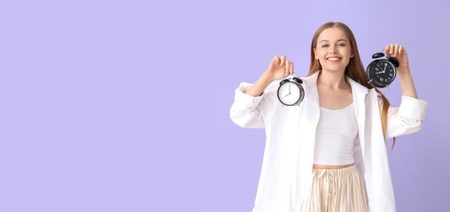 Happy young woman with alarm clocks on lilac background with space for text